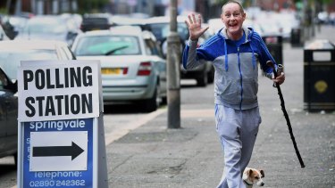 A man accompanied by his dog  makes his way into a polling station in Belfast.