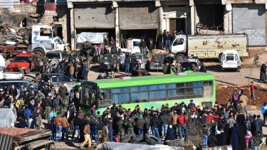 Residents gather near a green government bus for evacuation from eastern Aleppo.