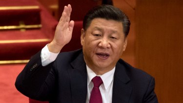 Chinese President Xi Jinping raises his hand to show approval of a work report during the closing ceremony for the 19th Party Congress