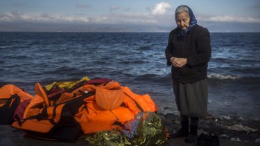 A local stands next to a pile of discarded life jackets after the arrival of refugees and migrants to the Greek island of Lesbos.
