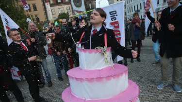 Satirical counter-demonstrators, including one dressed as Adolf Hitler and wearing a cake, pretend to celebrate the first anniversary of the first Pegida march.