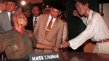 Then Indonesian president B.J. Habibie, centre, inspects a diorama depicting the murder of an Indonesian army general by alleged communists during a coup attempt in 1965. The coup attempt sparked the 1965 massacres of alleged communists.