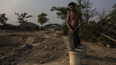 Ko Bo Bo collects what's left of the water in a small pond his family uses as a water source in Dala, Burma. 