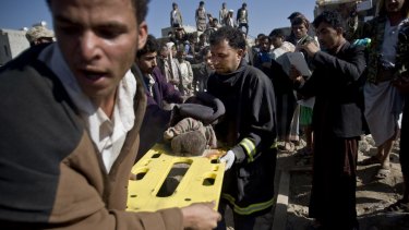 Yemenis carry the body of a child from  the rubble of houses destroyed by Saudi air strikes near Sanaa Airport on March 26.
