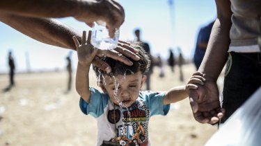Cooling down: A Syrian Kurd pours water on a child after they crossed the border between Syria and Turkey in September, fleeing from Islamic State fighters who advanced into their villages.