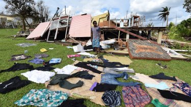 Adrian Banga's clothes lie on the ground as he stands in front of his destroyed house.