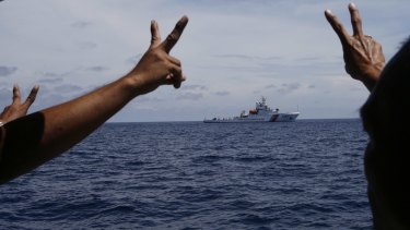 Philippine crewmen gesture towards a Chinese ship in the South China Sea
