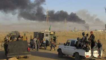 Smoke rises from Islamic State positions after an air strike by US-led coalition warplanes in Fallujah, as Iraqi security forces and allied Shiite and Sunni militias look on.