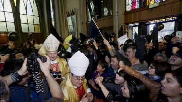 Protestors shout as bishops and priests enter the cathedral in Osorno.