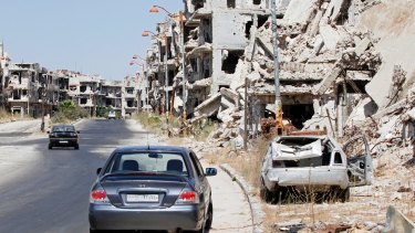 Damaged buildings and rubble line a street in the Syrian city of Homs on Monday.