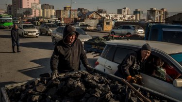 Sellers negotiate the price of raw coal with potential customers in a car at the Shar Khad market in Ulaanbaatar, Mongolia.
