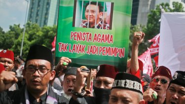 Muslim protesters shout slogans as they hold up a placard with a picture depicting Jakarta Governor Basuki "Ahok" Tjahaja Purnama behind bars.