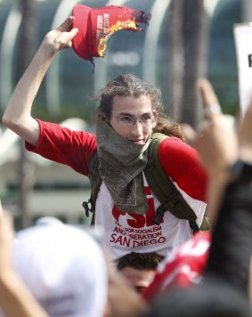 An anti-Trump protester hold a Trump campaign hat that has been set on fire as protesters and Trump supporters clash near in San Diego last month.