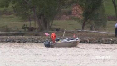 A boat searches the Tweed River for the car which slid off the road about 1.40pm.