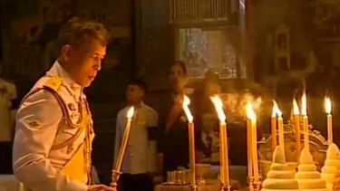 In this image made from video, Thailand's new King Maha Vajiralongkorn Bodindradebayavarangkun lights candles for his father at the Grand Palace in December.