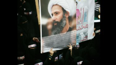 Saudi anti-government protesters carry a poster of cleric Nimr al-Nimr in 2012.