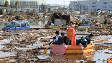Students use a rubber raft to get food from their dormitory that submerged following the catastrophic earthquake and tsunami.