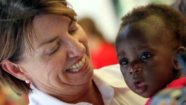 Anna Bligh cuddles David Mitima on January 13, 2011, during a visit to one of the evacuation centres at Queensland Sports and Athletic Stadium in Nathan.
