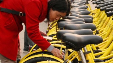 A Beijing commuter unlocks her share bike.