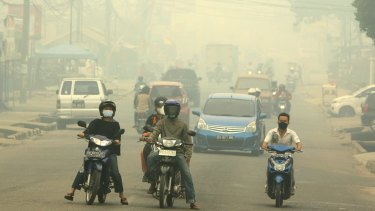 Motorists ride on a road as haze from wildfires blankets the city in Jambi, Indonesia.