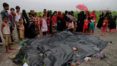 Bangladeshi villagers gather around the covered bodies of Rohingya women and children who died after their boat capsized.
