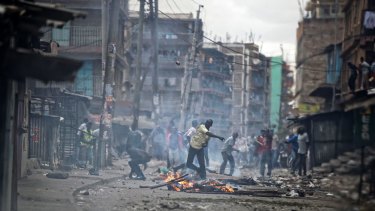 A protester throws an unexploded tear gas grenade back to the police, during clashes in the Mathare area of Nairobi.