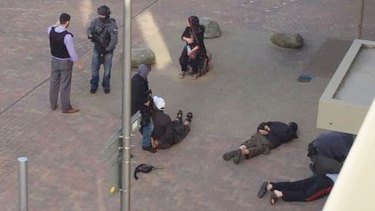 People lie on the ground after being detained by police at Elizabeth Fry apartments in Barking, east London, which officers raided.
