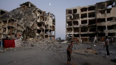A Palestinian plays in a courtyard near destroyed buildings at a residential neighbourhood in Beit Lahiya, northern Gaza Strip, in August 2014. 