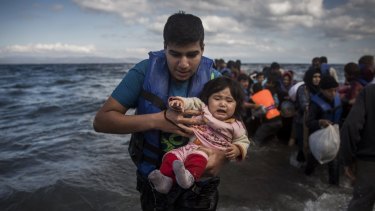 A man and a baby disembark from a dinghy after travelling from the Turkish coast to the north-eastern Greek island of Lesbos.