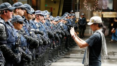 A protester takes photos of Victoria Police's Public Order Response Team