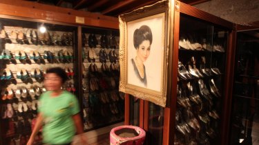 A Marikina Shoe museum worker passes a portrait of former First Lady Imelda Marcos hanging next to hundreds of her shoes in Marikina City, east of Manila, Philippines.