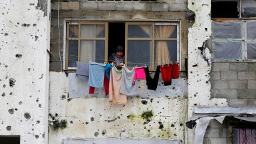 A Palestinian woman hangs clothes outside her apartment in the Gaza Strip. The building was partially destroyed during the 2014 Israeli bombardment of the besieged enclave.