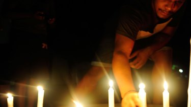 A candlelight vigil is held in the street where eight children died in a multiple stabbing in the suburb of Manoora.