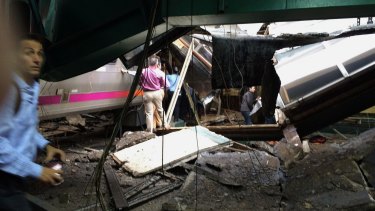 People examine the wreckage of a New Jersey Transit commuter train that crashed into the train station during the morning rush hour in Hoboken, New Jersey 