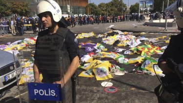 Bodies of victims are covered with flags and banners as a police officer secure the area after the explosion in Ankara.