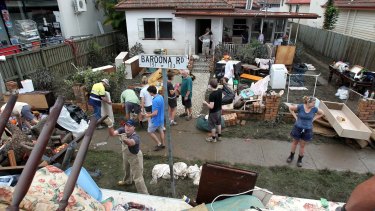 Teams of volunteers descend on flood-affected suburbs to clean up.