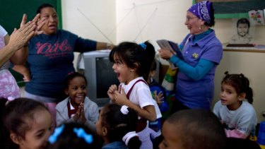 Students and teachers celebrate after listening to a live, nationally broadcast speech by Cuba's President Raul Castro about the country's restoration of relations with the United States, at a school in Havana, Cuba.