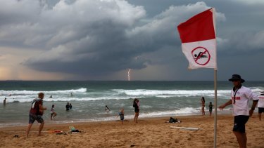 Wollongong City Council Lifeguard Jake Spooner raises the no swim flag, closing Austinmer beach as a Southerly storm moves up the coast.