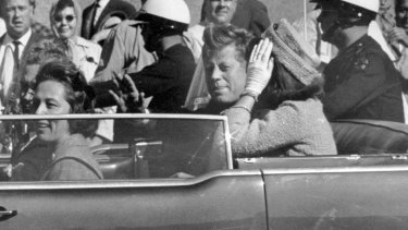 President John F. Kennedy waves from his car in a motorcade approximately one minute before he was shot in Dallas in 1963.