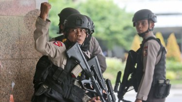 A police officer gives a hand signal to a squad mate as they search a building near the site of an explosion in Jakarta, Indonesia on Thursday.
