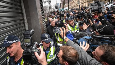 Police help George Pell through the 100-strong crush of national and international media in July.