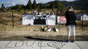 A woman visits a makeshift memorial near the road leading to Umpqua Community College in Roseberg after the mass shooting there.