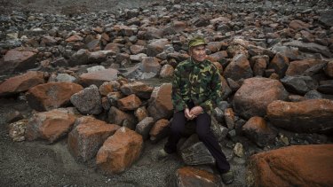 Chinese villager Li Yuanqing, 62, who has witnessed the ice slowly receding, sits near the headwaters of the Glacier River in Sichuan earlier this month. 
