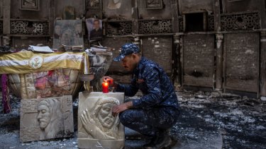 A member of the Iraqi federal police lights a candle inside a church destroyed by Islamic State in Qaraqosh, Iraq.