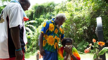Eddie Mabo's daughter, Celuia Mabo, is comforted by William Bero, centre, and Evan Noah, at the grave of her father.