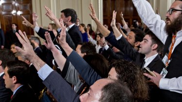 Members of the media raise their hands to ask a question to US President Donald Trump.