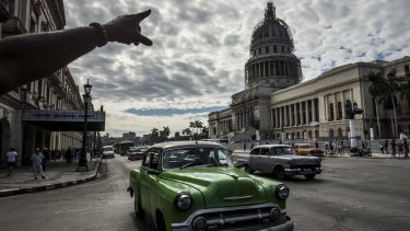 Open for business: Classic cars drive down the Paseo de Marti in front of Cuba's National Capitol Building in Havana.