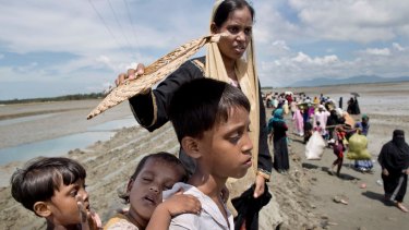 Foriza Begum holds a fan to shield her son Yosar Hossein, 7, and daughter Noyem Fatima, 2, on their way to a Bangladesh army run processing centre.