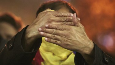A man with a Romanian flag wrapped around his neck holds his palms in front of his face during the fourth day of protests.