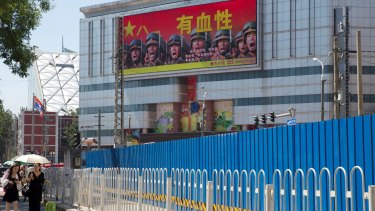 People walk near a billboard of the Chinese military reading "courageous", in Beijing, last month. Beijing is intensifying its warnings to Indian troops to get out of a contested region high in the Himalayas where China, India and Bhutan meet.